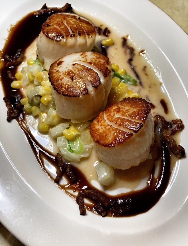 Seared scallops over corn and drizzled with balsamic glaze
