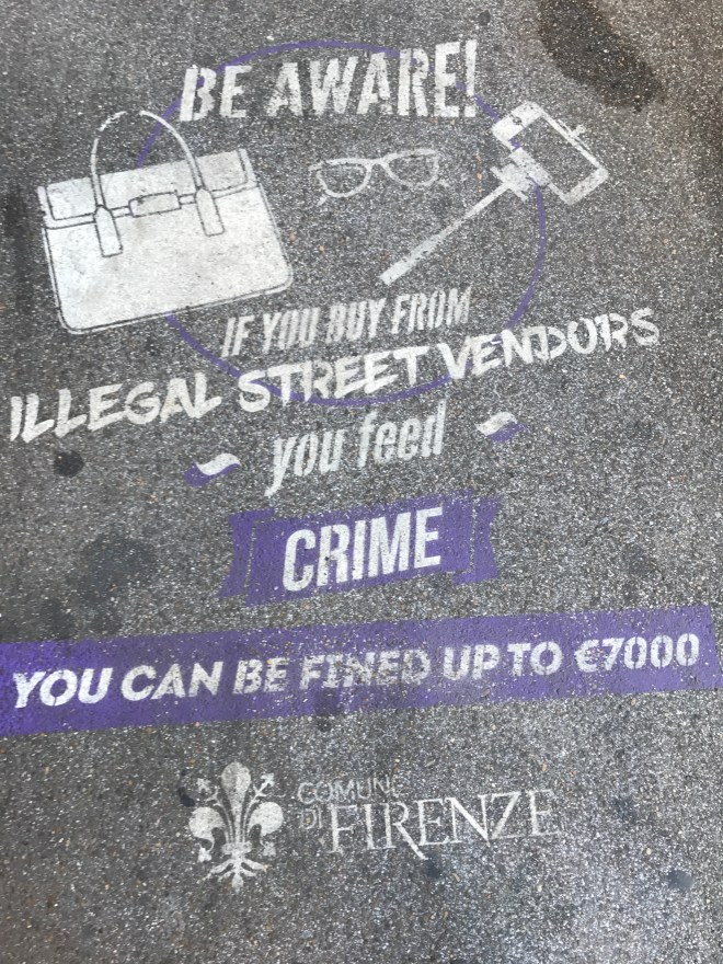 sidewalk warning visitors not to buy from illegal street vendors