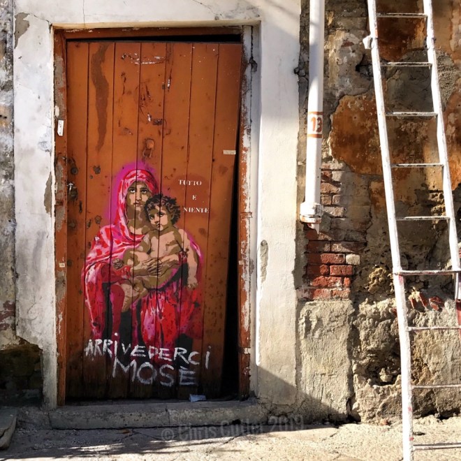 Decaying wooden door with graffiti of Blessed Mother and Jesus