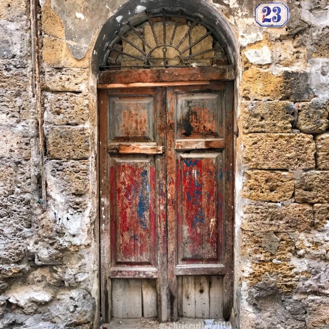 Old wooden door with peeling red and blue paint.