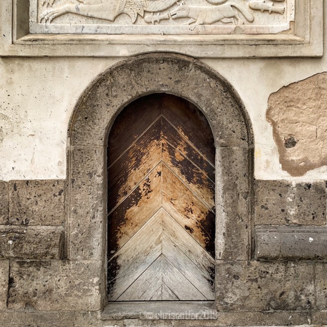 Arched wooden door with fading brown stain