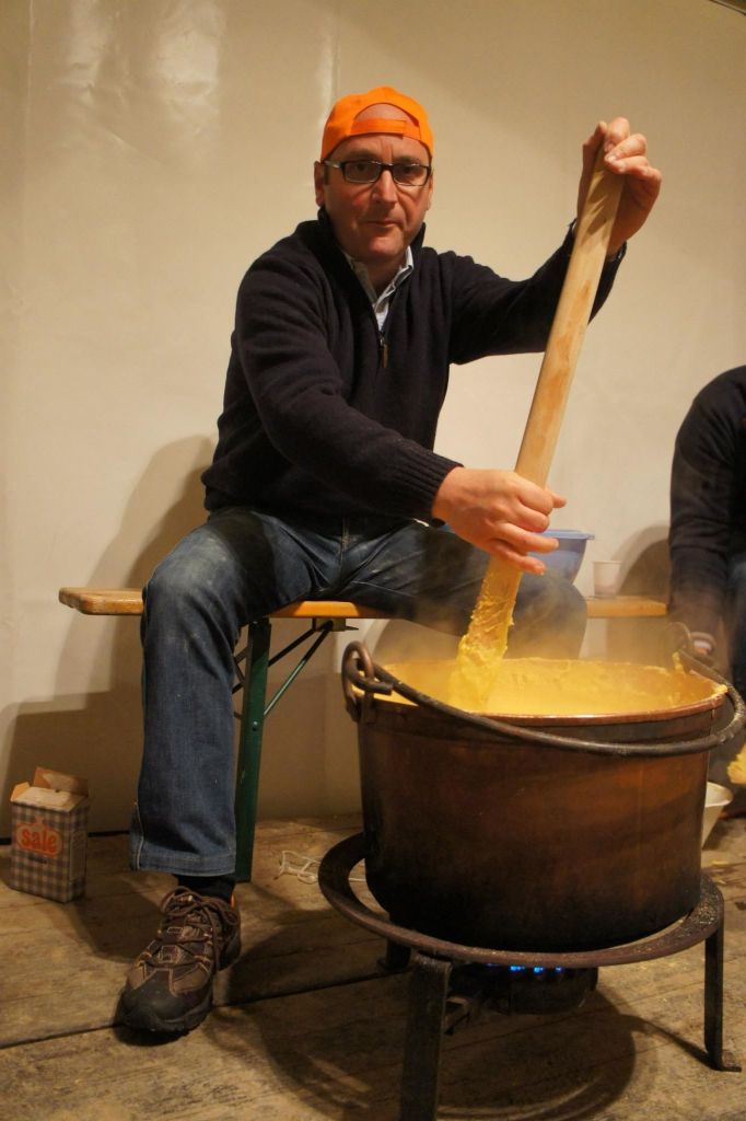 A man stirring polenta in a large copper pot