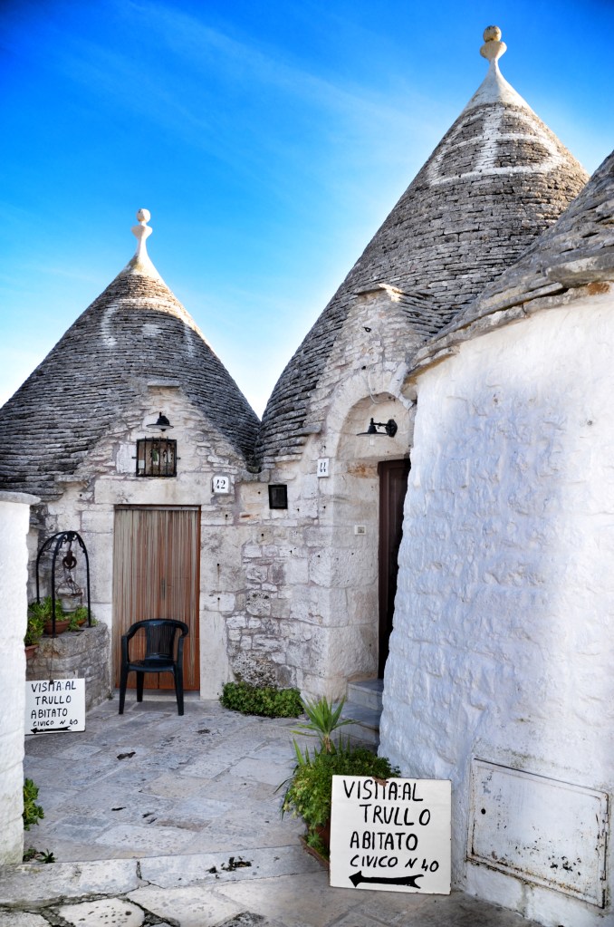 Two trulli with signs inviting tourists to tour an inhabited one