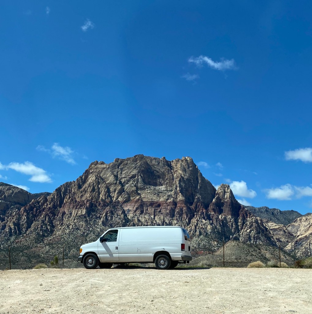 white van, calico mountain behind it, blue sky